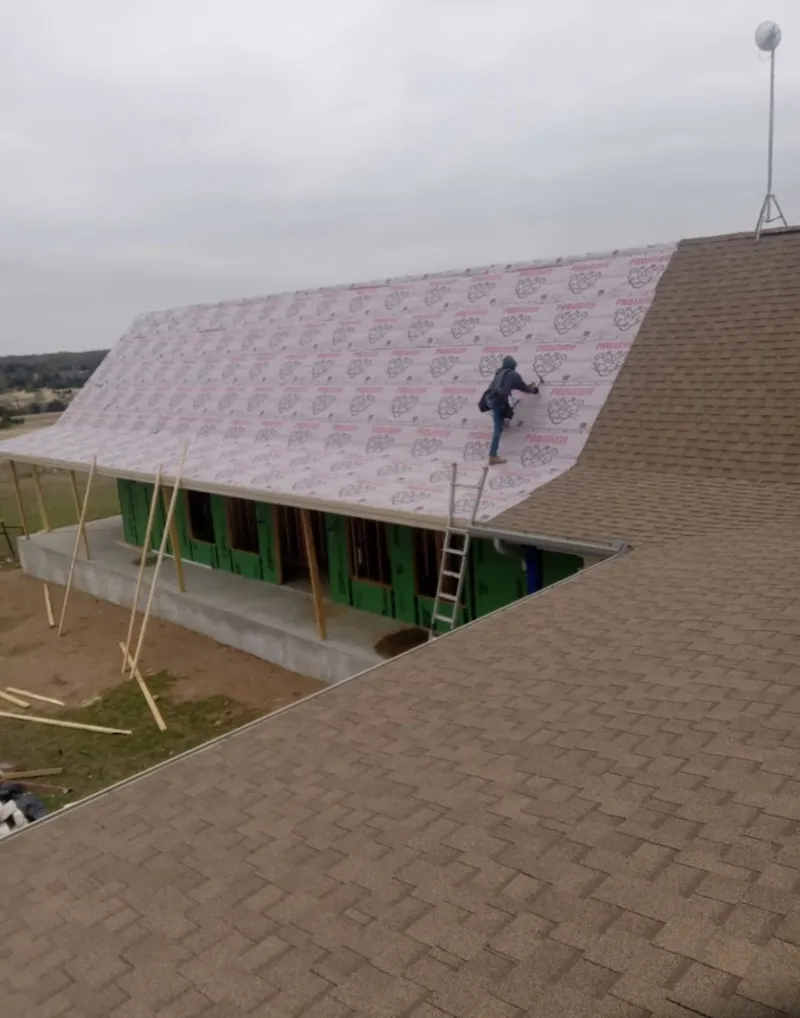 Worker preparing underlayment for a metal roof installation in Gulf Hills